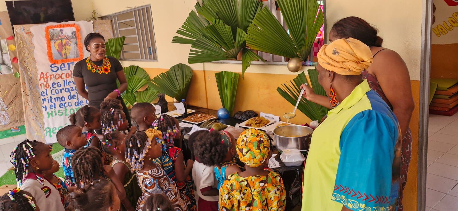 Niños afrocolombianos en trajes típicos y mujeres compartiendo gastronomía ancestral en evento cultural organizado por Manos Amigas
